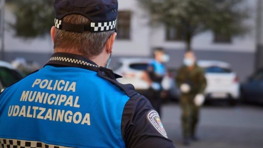 Agente de policía municipal de espaldas con un uniforme de color azul.
