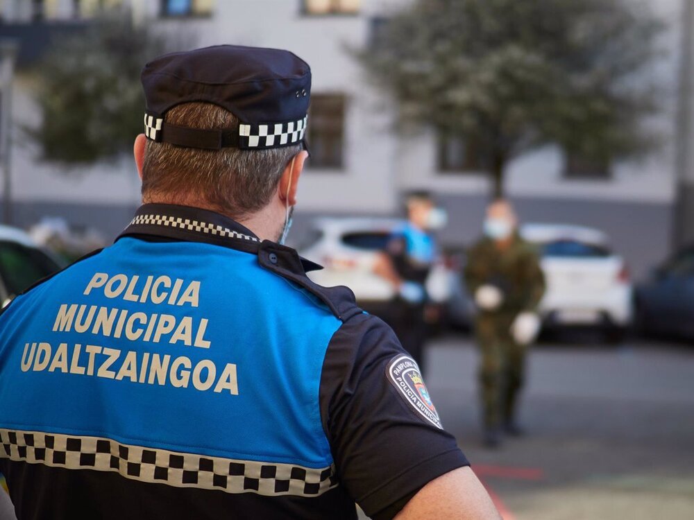 Agente de policía municipal de espaldas con un uniforme de color azul.